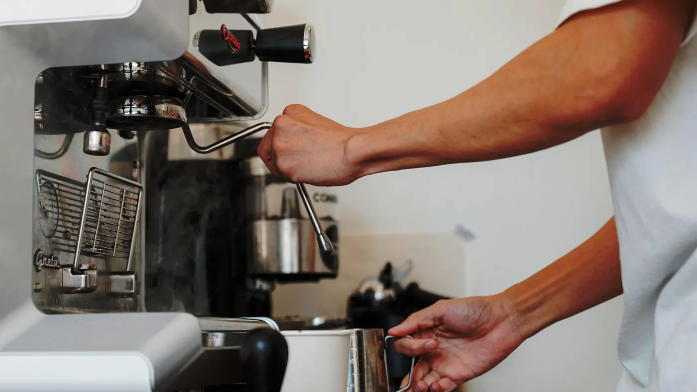 Ruky baristu pri príprave espressa na kávovare Astoria